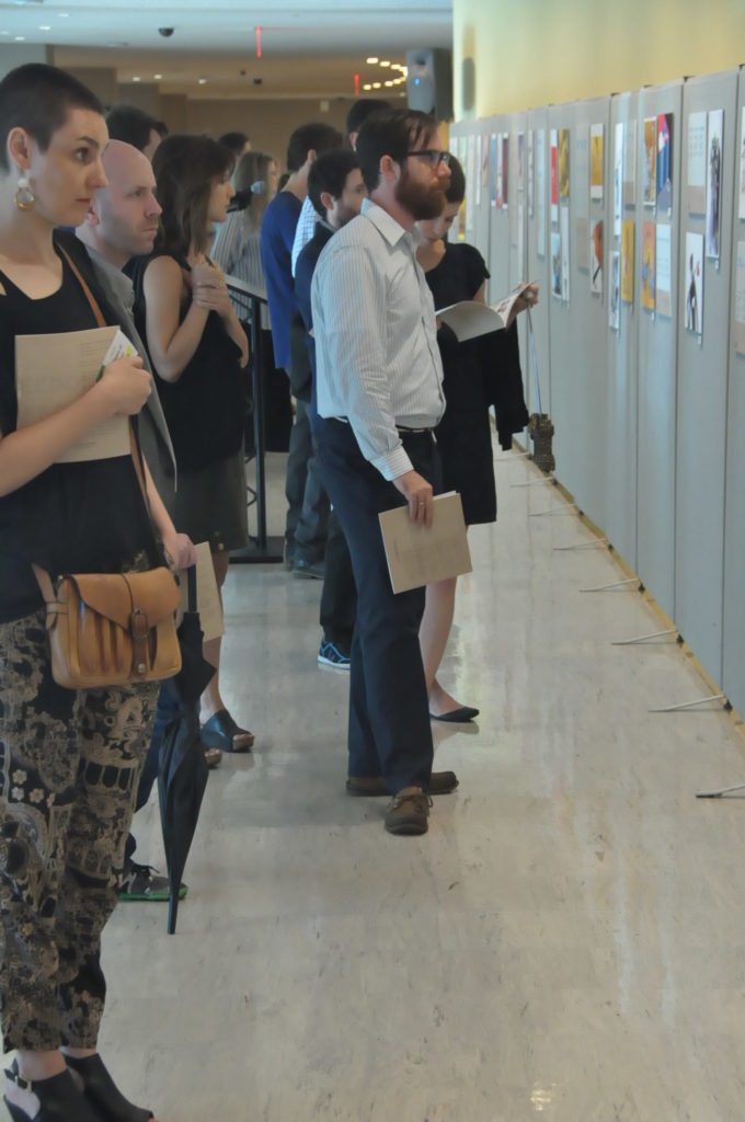 Plusieurs convives admirant les dessins de l'exposition